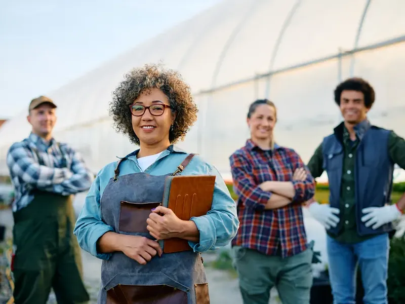 Smiling greenhouse growers team standing together outdoor for business directory listing